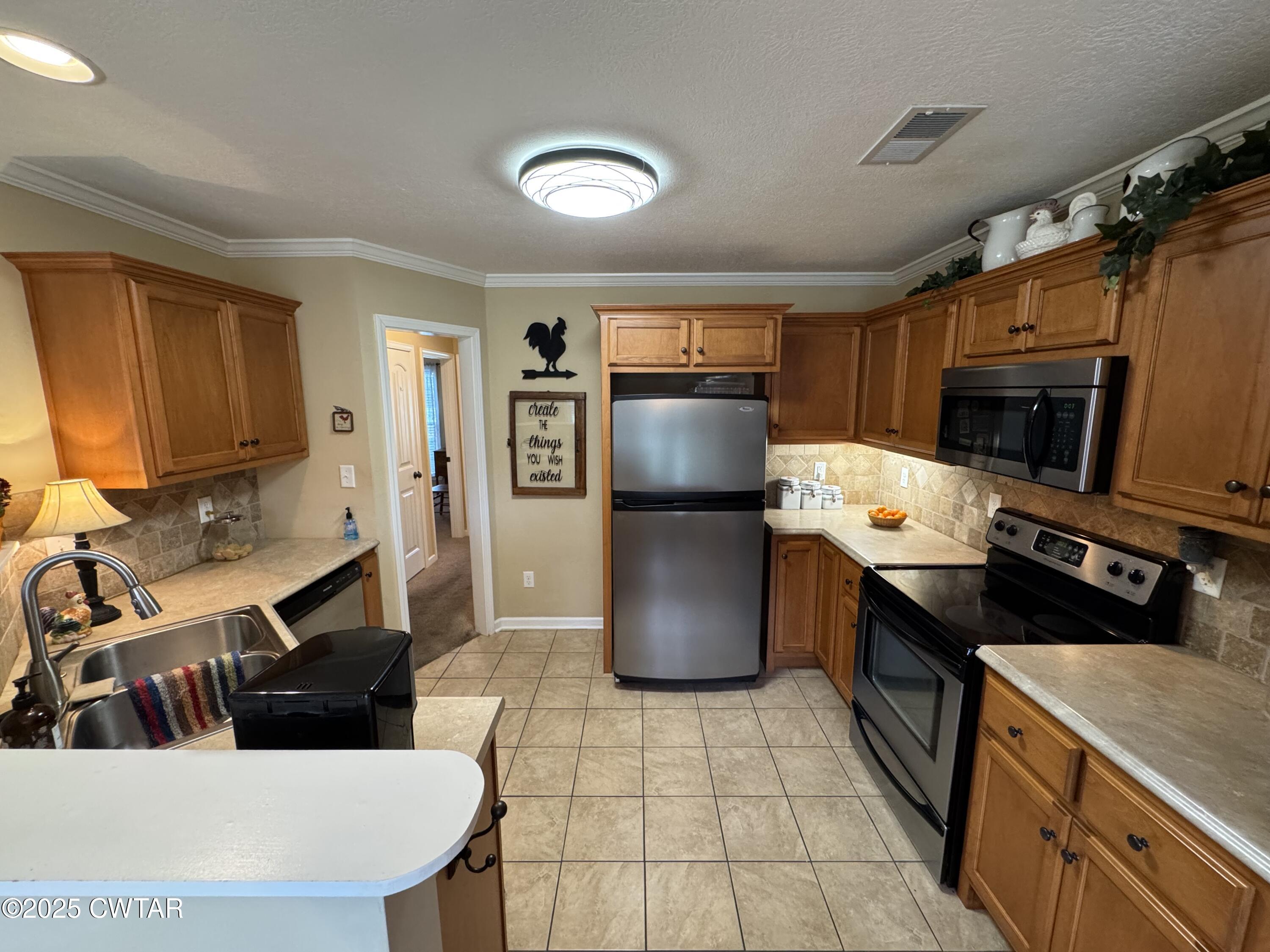 5111 Rolling Meadow Milan, TN 38358 - Photo 18 of 36 a kitchen with a sink a stove top oven a refrigerator cabinets and a dining table