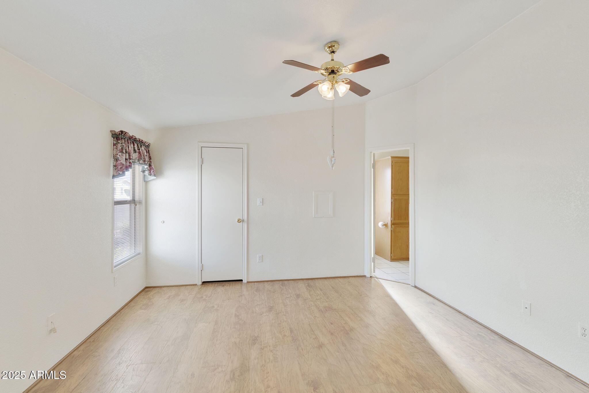 3700 South Tomahawk Road, Unit 80 Apache Junction, AZ 85119 - Photo 24 of 41 an empty room that has a chandelier fan and wooden floor