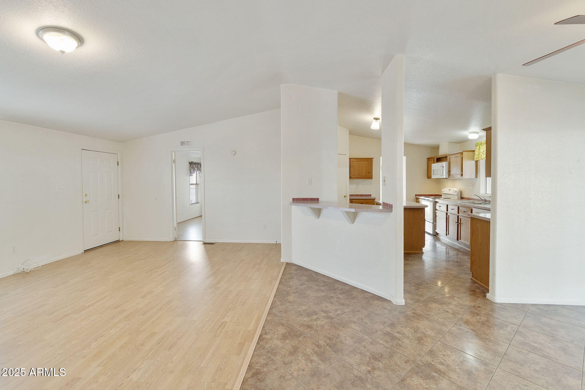 3700 South Tomahawk Road, Unit 80 Apache Junction, AZ 85119 - Photo 25 of 41 an empty room with kitchen view and wooden floor