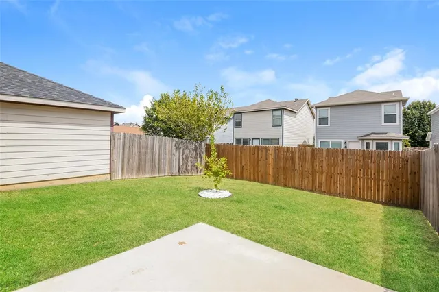 a backyard of a house with plants and wooden fence