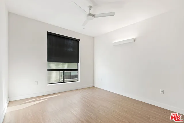 a view of an empty room with a window and wooden floor