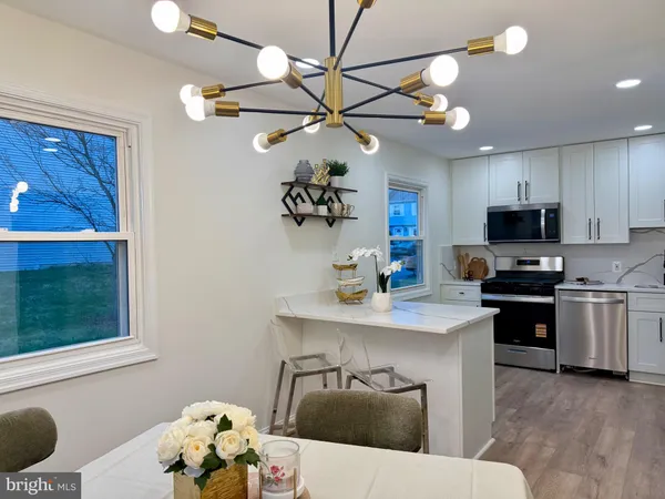a kitchen with stainless steel appliances kitchen island granite countertop a refrigerator a sink dishwasher a dining table and chairs with wooden floor