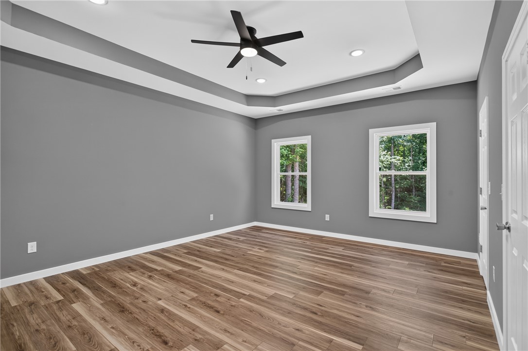 223 Maple Drive Anderson, SC 29621 - Photo 17 of 45 Recessed lighting illuminates this room, showcasing rich hardwood flooring and a stylish tray ceiling.
