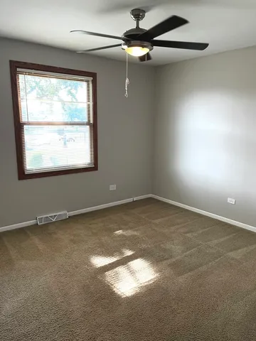 an empty room with a window and a fan