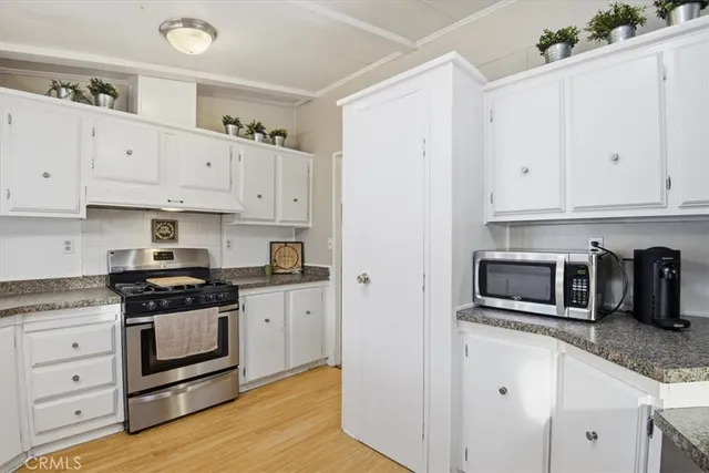 a kitchen with granite countertop white cabinets and stainless steel appliances