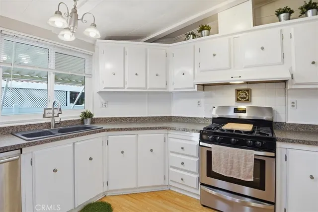 a kitchen with granite countertop white cabinets white stainless steel appliances and a sink