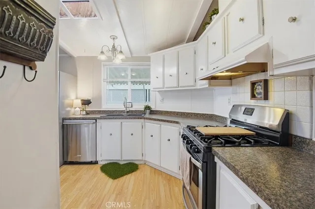 a kitchen with stainless steel appliances granite countertop a sink a stove and a cabinets