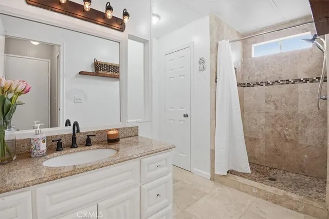 a bathroom with a granite countertop sink a mirror and shower