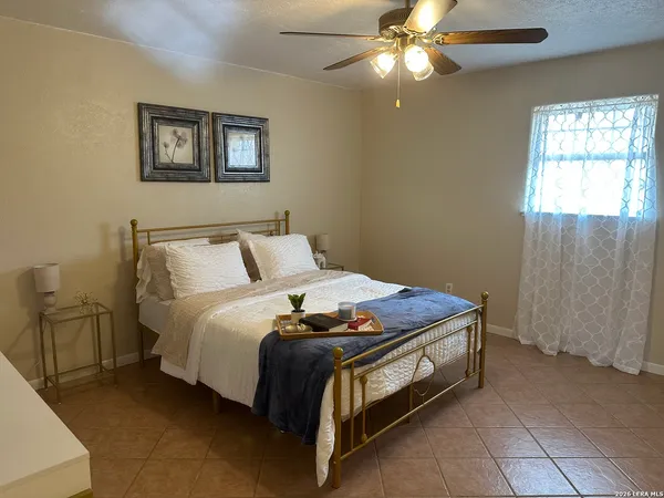 a bed sitting in a bedroom next to a window and a chandelier