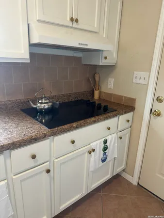 a kitchen with white cabinets and sink