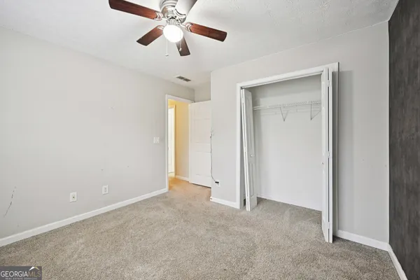 an empty room with closet and a chandelier fan