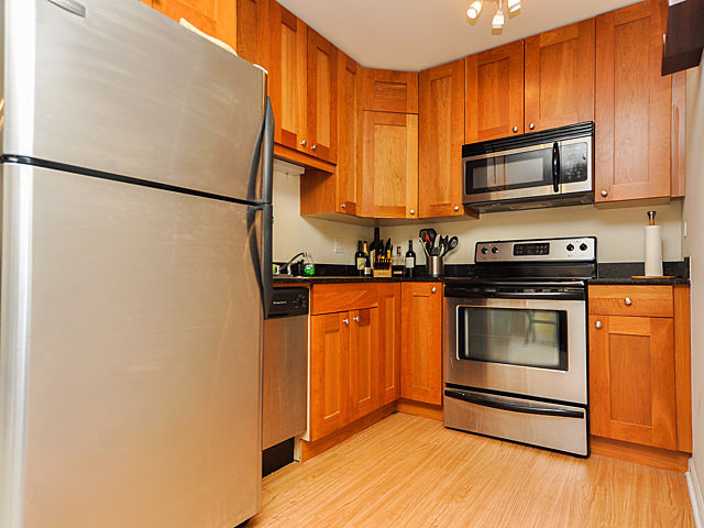 3033 North Sheridan Road, Unit 708 Chicago, IL 60657 - Photo 6 of 8 a kitchen with granite countertop a refrigerator stove and microwave