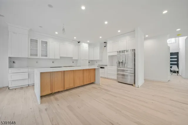 a large kitchen with stainless steel appliances kitchen island granite countertop a stove a sink and white cabinets