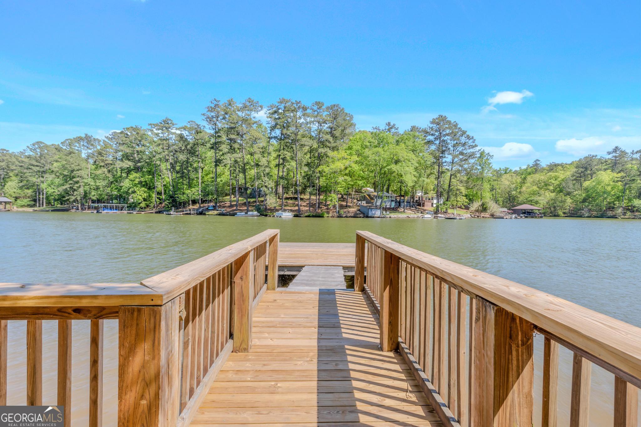 136 Yancey Road Jackson, GA 30233 - Photo 28 of 37 a view of a lake with wooden stairs and bridge and tall trees