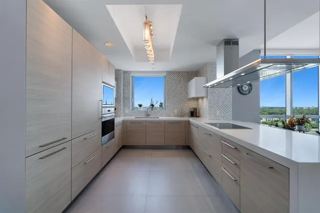a large white kitchen with a large window and stainless steel appliances
