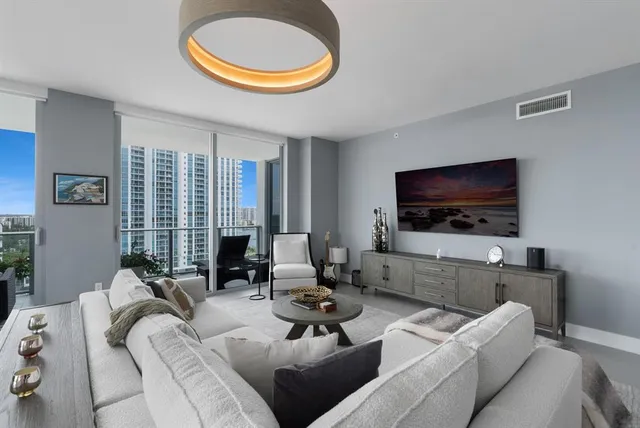 a living room with furniture a flat screen tv and a large window