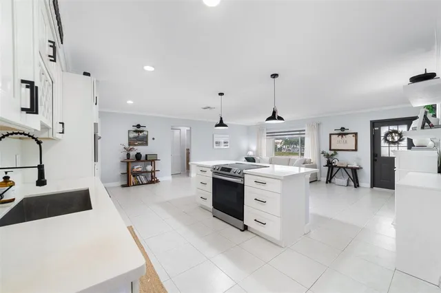 a large white kitchen with a stove a sink dishwasher and a refrigerator with wooden floor