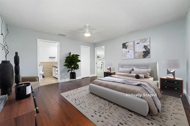 a spacious bedroom with a bed a dresser and wooden floor