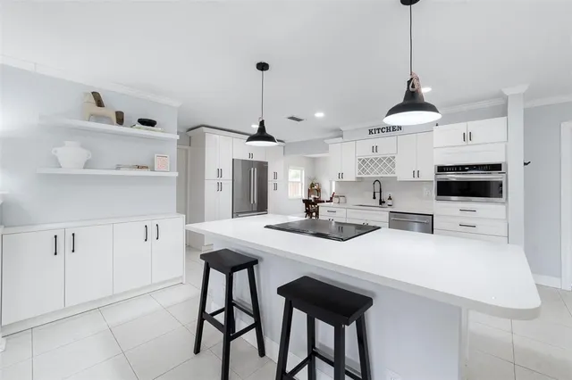 a kitchen with stainless steel appliances kitchen island granite countertop a table chairs and a refrigerator