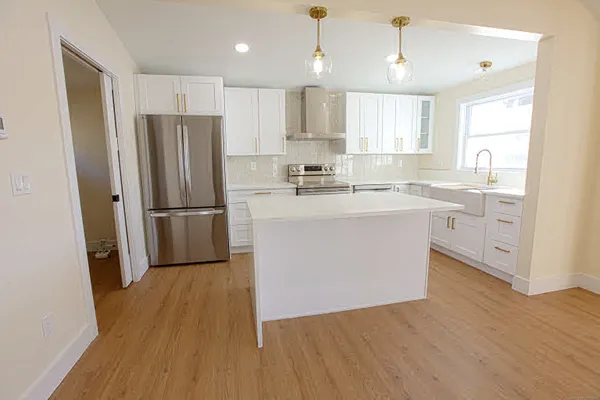 a kitchen with wooden floors white cabinets and stainless steel appliances