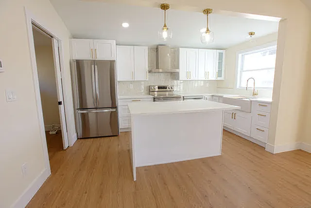 a kitchen with wooden floors white cabinets and stainless steel appliances