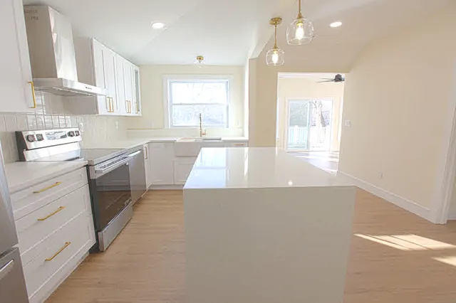 a large kitchen with stainless steel appliances a large window a sink and cabinets