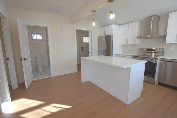 a kitchen with stainless steel appliances granite countertop a refrigerator a sink a stove and white cabinets