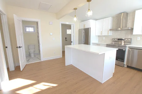 a kitchen with stainless steel appliances granite countertop a refrigerator a sink dishwasher a stove and white countertops with wooden floor