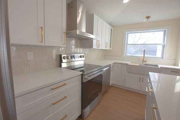 a kitchen with a sink dishwasher a stove and white cabinets