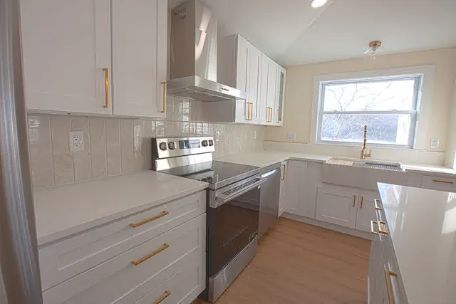 a kitchen with a sink dishwasher a stove and white cabinets