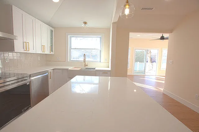 a view of a kitchen with a sink and dishwasher a stove top oven with wooden floor