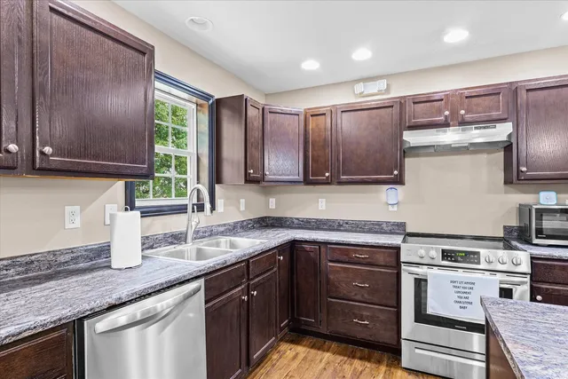 a kitchen with stainless steel appliances granite countertop wooden cabinets a stove top oven a sink and dishwasher