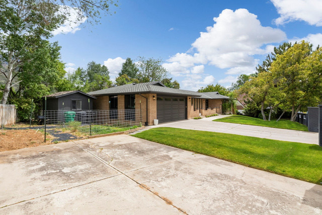 4150 Dover Lane Provo, UT 84604 - Photo 40 of 44 Brick exterior with an attached garage, featuring a concrete driveway and a grassy front lawn