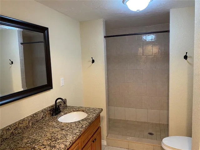 a bathroom with a granite countertop sink toilet and shower