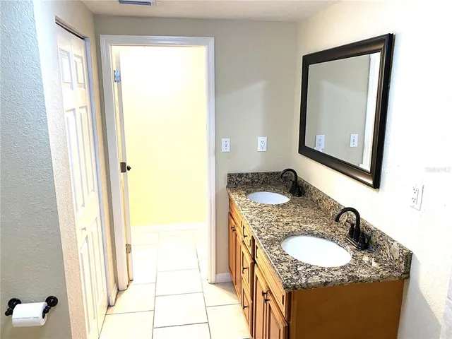 a en suite bathroom with a granite countertop sink and a mirror