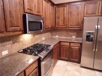 a kitchen with granite countertop stainless steel appliances a stove a refrigerator and cabinets