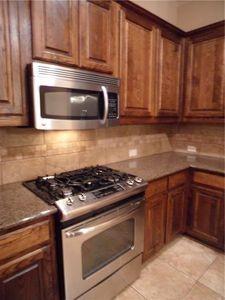 5321 Locust Drive McKinney, TX 75070 - Photo 3 of 17 a kitchen with granite countertop wooden cabinets and stainless steel appliances