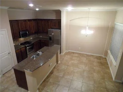 a kitchen with granite countertop a refrigerator and a stove top oven
