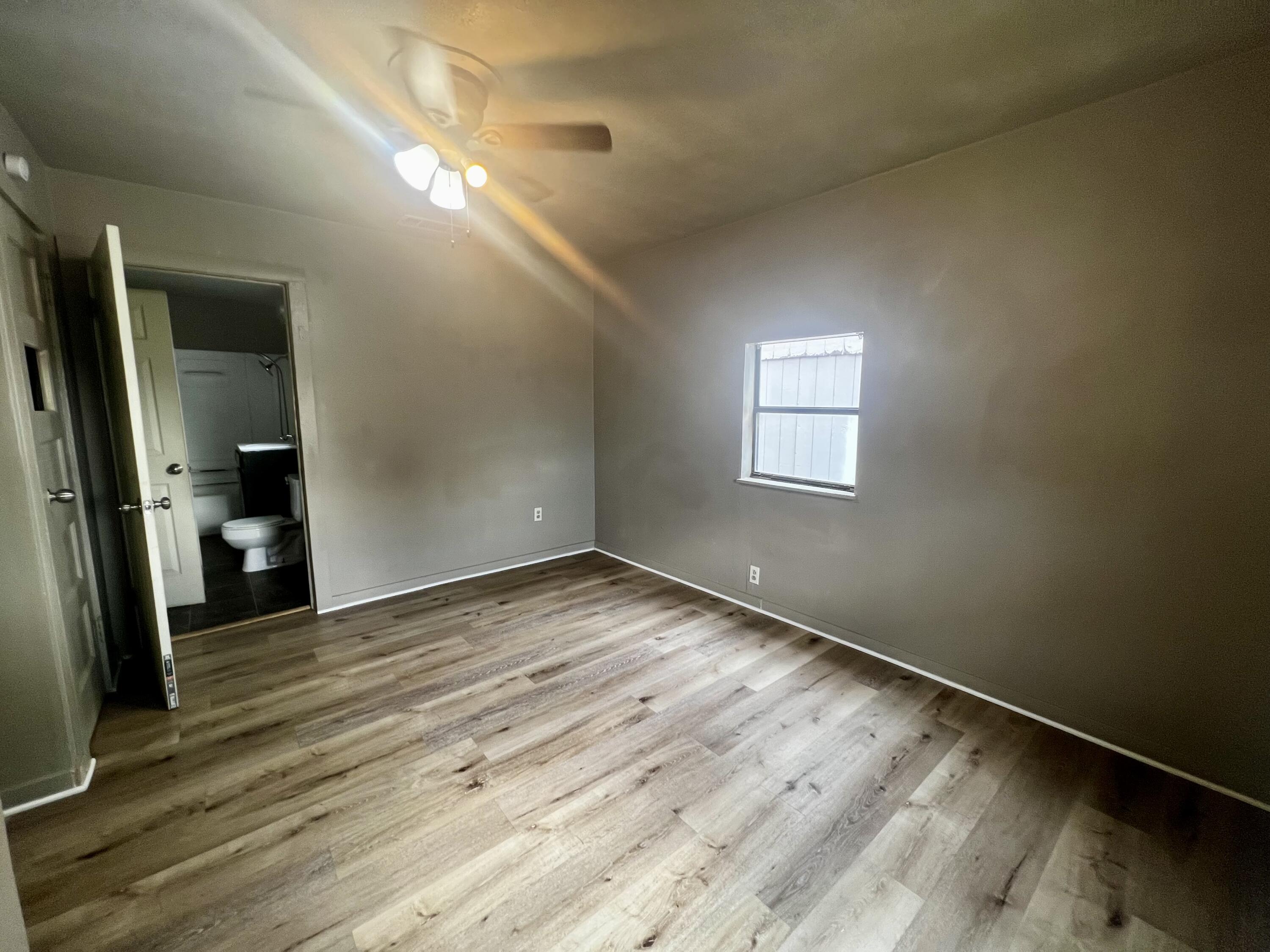 220 North 6th Street Slaton, TX 79364 - Photo 3 of 8 an empty room with wooden floor and windows