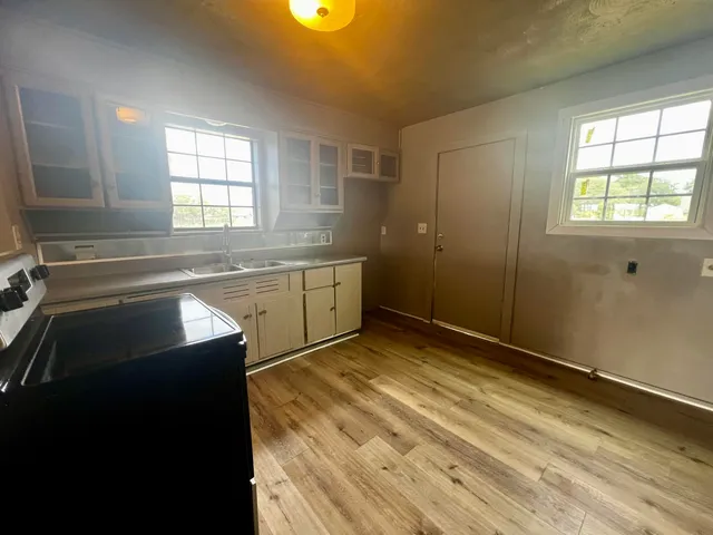 a view of a kitchen with wooden floor and windows