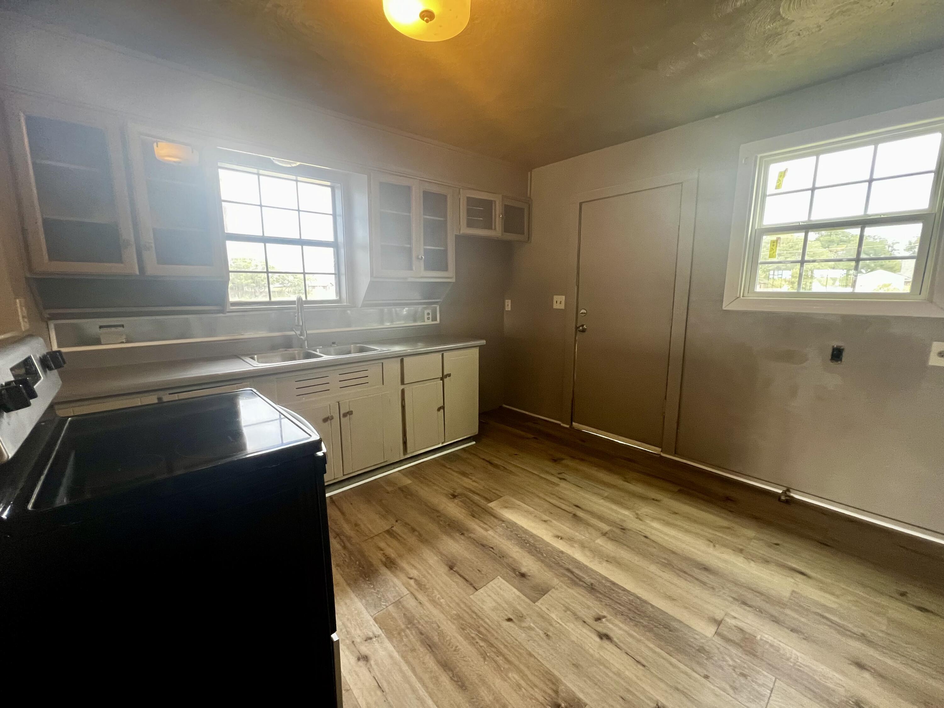 220 North 6th Street Slaton, TX 79364 - Photo 5 of 8 a view of a kitchen with wooden floor and windows