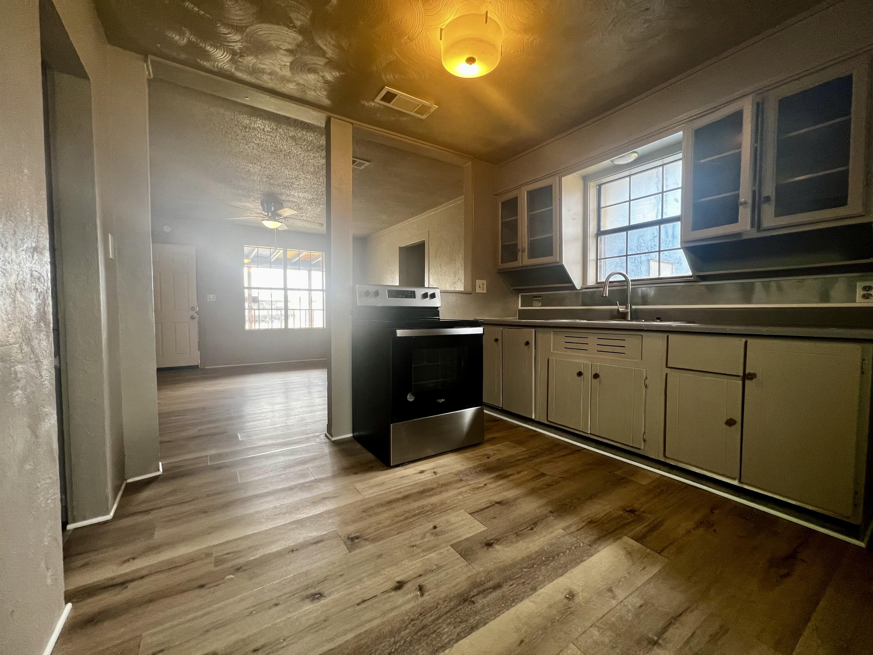 220 North 6th Street Slaton, TX 79364 - Photo 6 of 8 a kitchen with stainless steel appliances granite countertop a sink cabinets and wooden floor