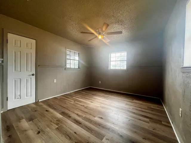 en empty room with windows and ceiling fan