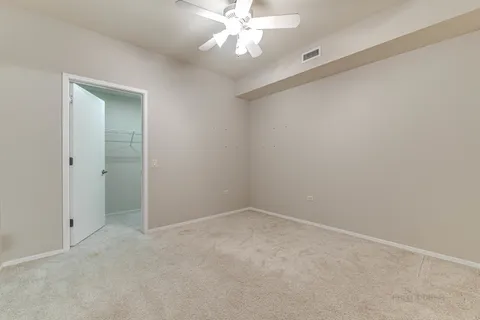 an empty room with a chandelier fan and closet area