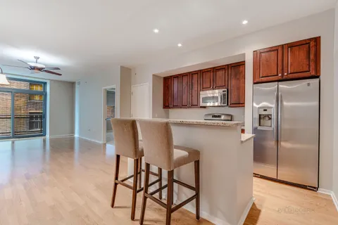 a kitchen with stainless steel appliances granite countertop a refrigerator a stove a microwave oven with cabinets and wooden floor