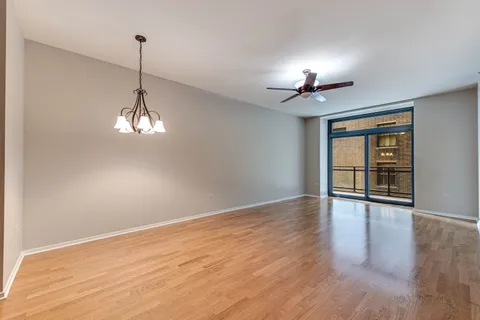 a view of empty room with wooden floor and chandelier