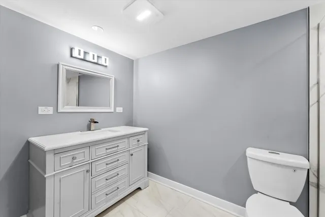 a bathroom with a toilet sink vanity and mirror