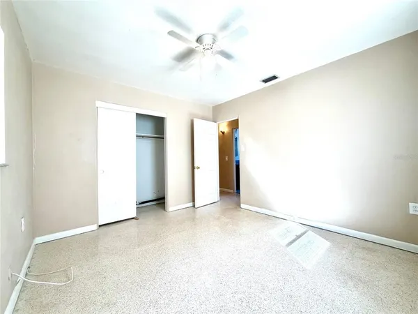 an empty room with closet and a ceiling fan