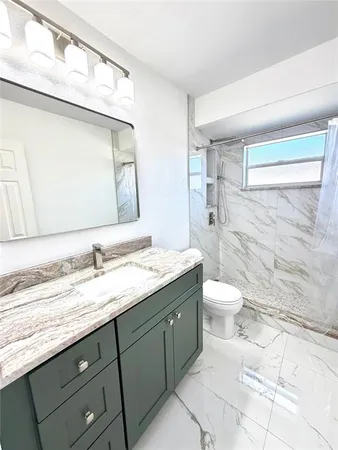 a bathroom with a granite countertop sink a toilet and a mirror