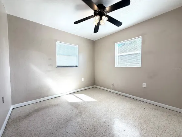 an empty room with windows and fan